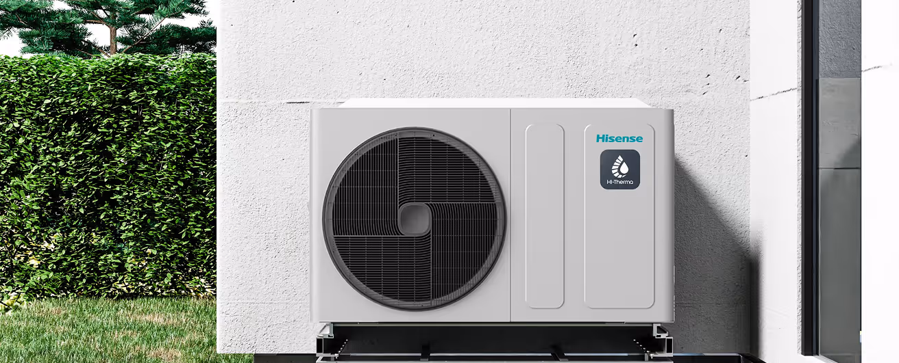 Unidad exterior de aire acondicionado Hisense instalada en fachada blanca junto a jardín con césped y arbustos.