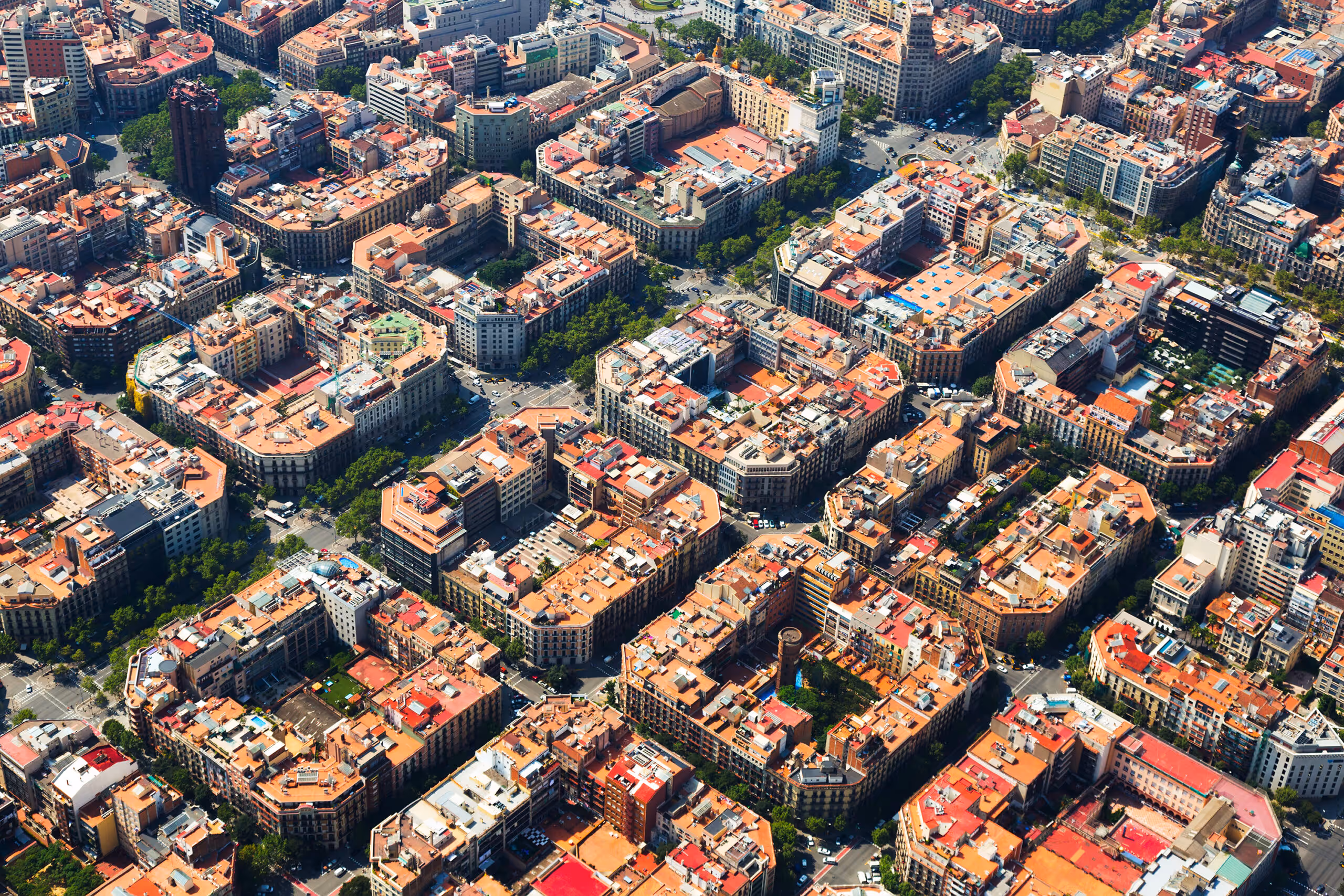Vista aérea del distrito de Eixample en Barcelona con bloques de edificios y calles en cuadrícula.