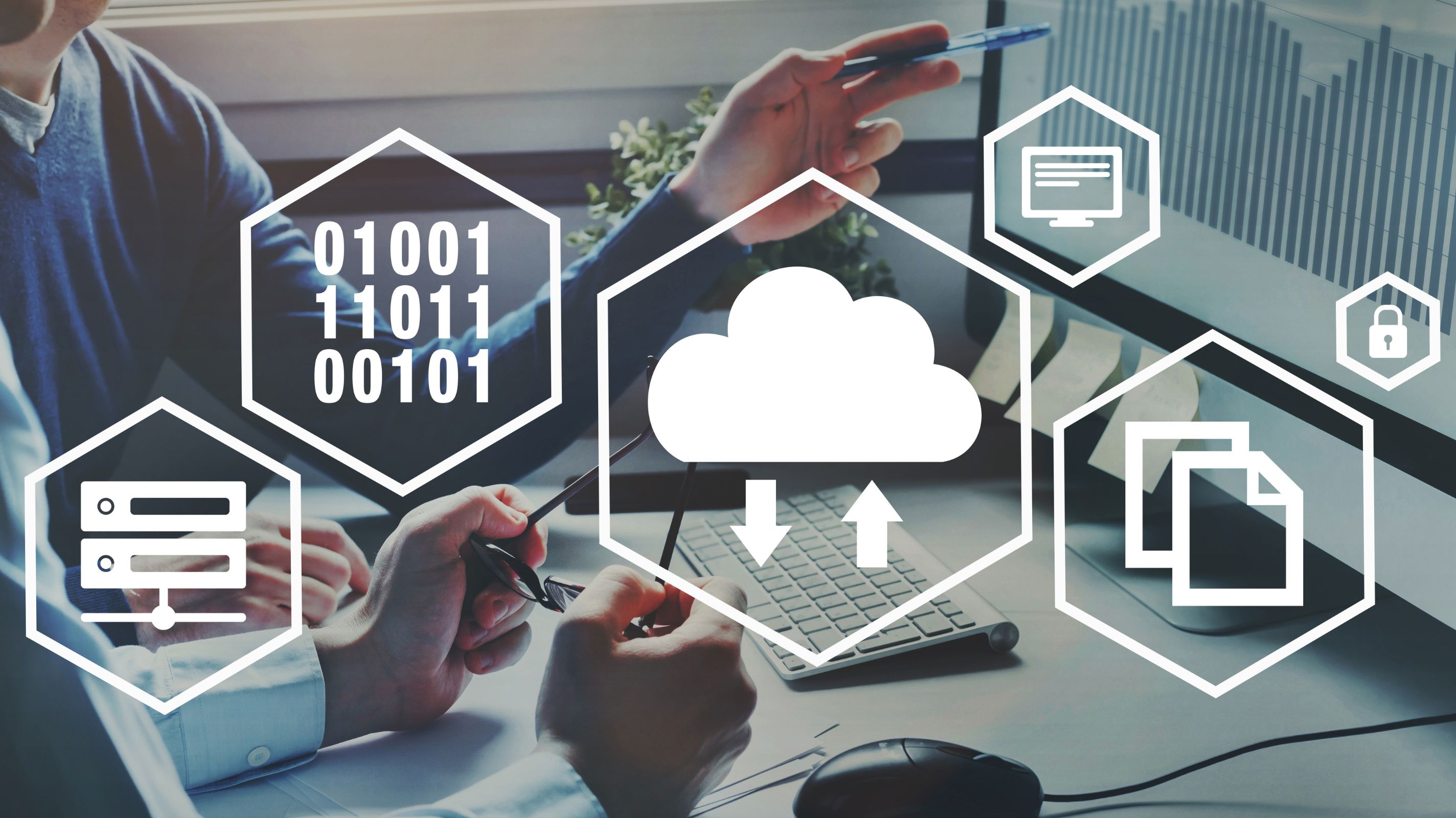 Two people discussing in front of a computer monitor with digital icons representing cloud storage, data transfer, security, files, and binary code overlaid.