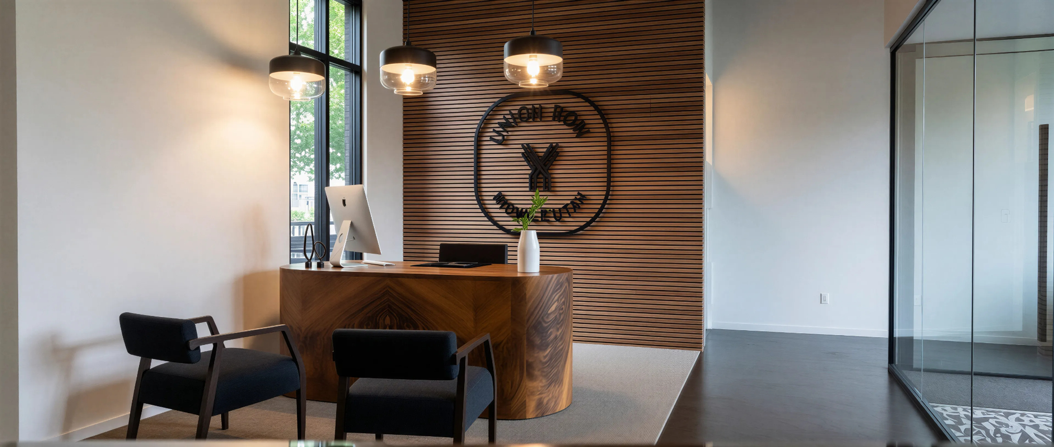 Rendering of reception with front desk with computer and chairs featuring Union Row logo on wall