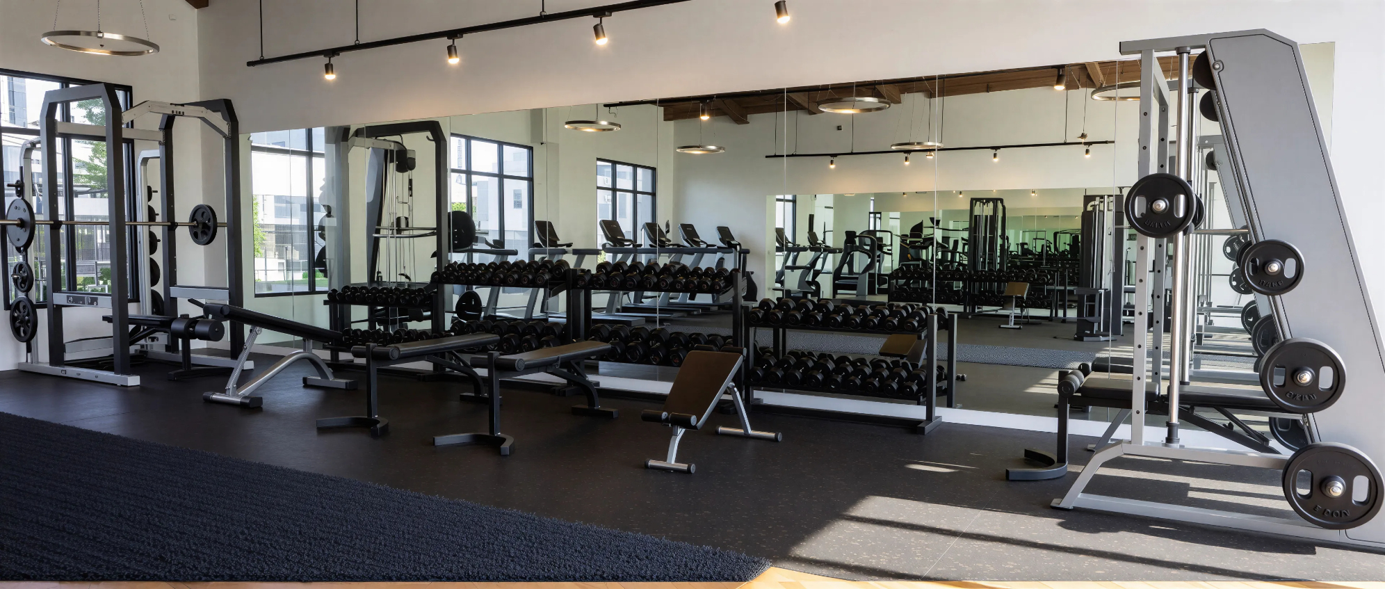 Rendering of gym with wall mirrors, dumbbells, and weight benches