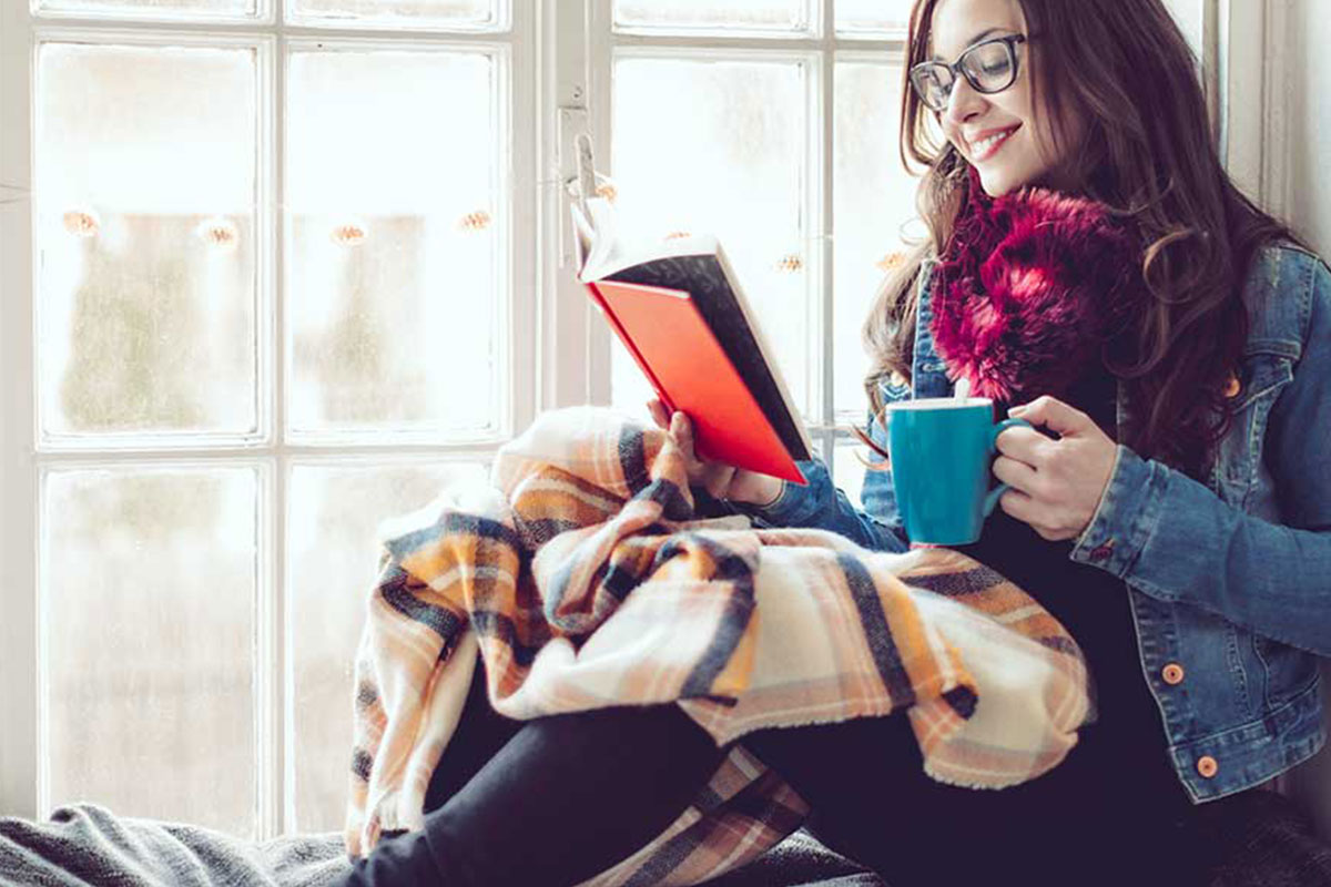 girl reading in her book nook on cozy winter day