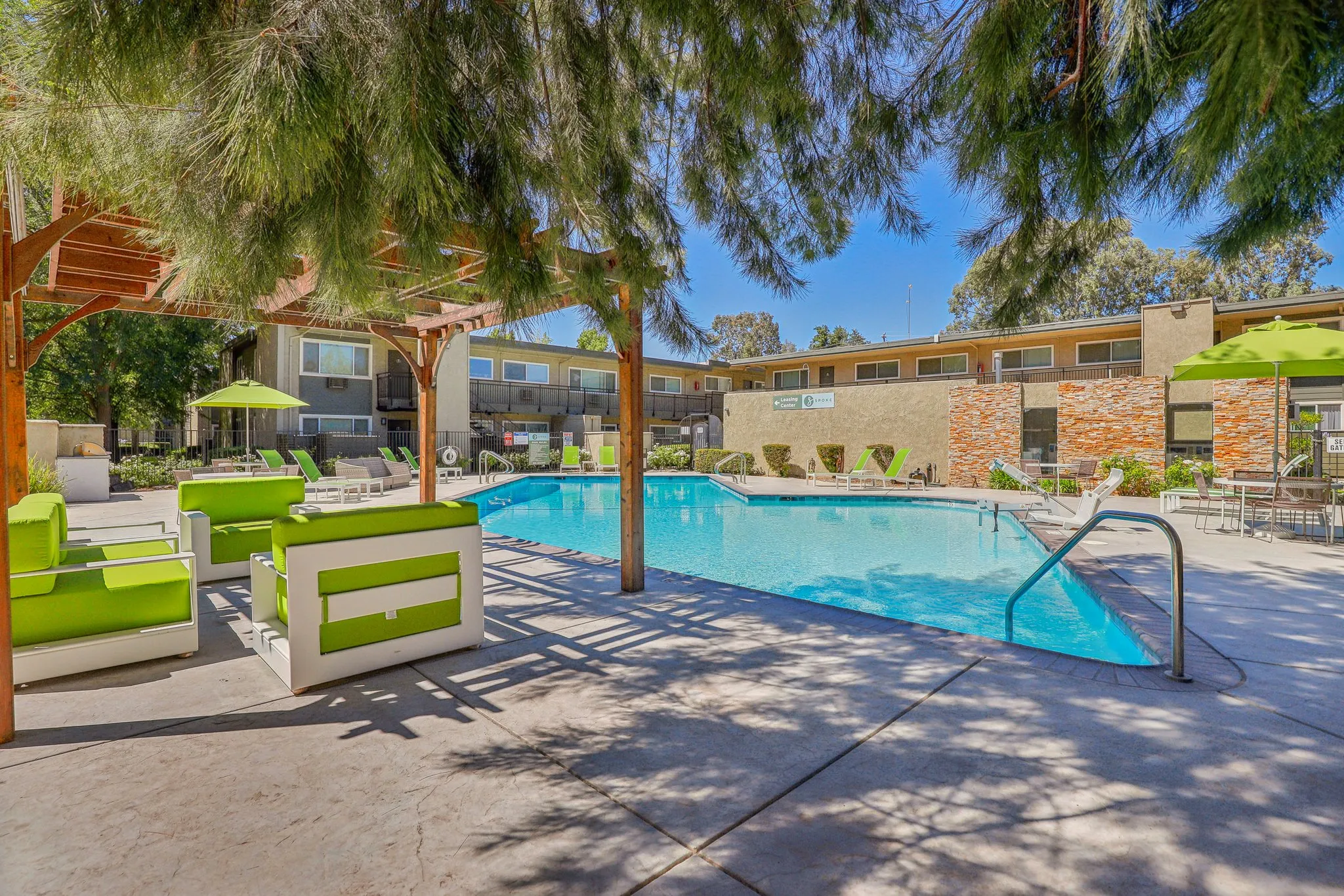Pool with view of lounge chairs, cabana, and table with umbrella