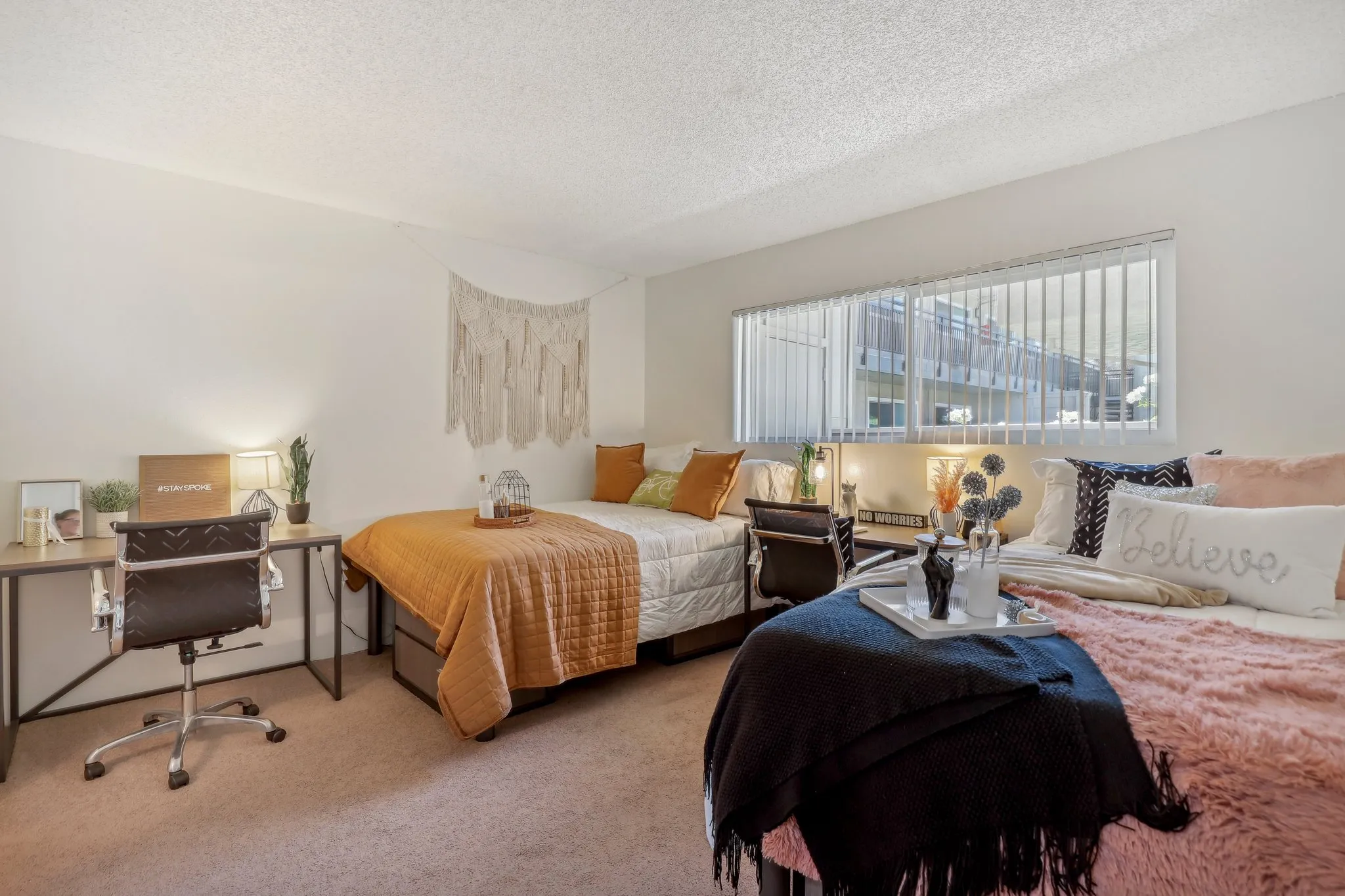 bedroom with two beds, two desks and chairs, and large window