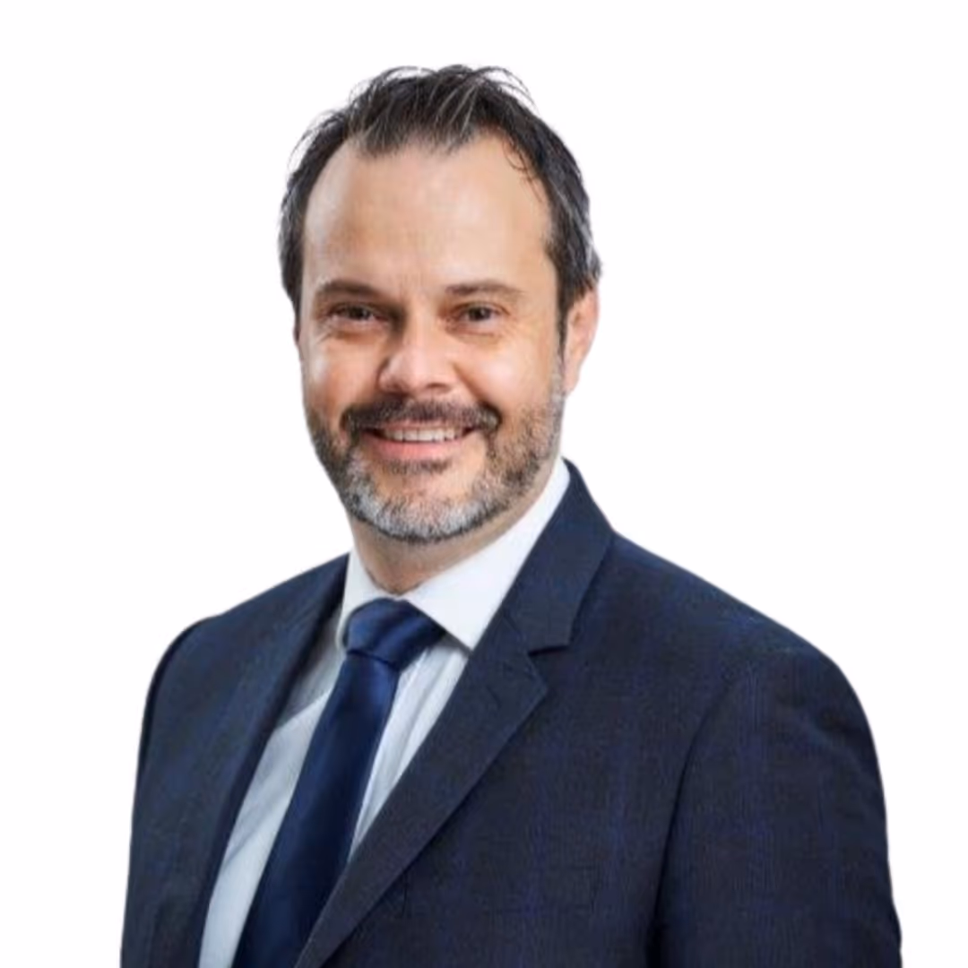 Homme souriant portant un costume bleu marine avec une chemise blanche et une cravate bleue.