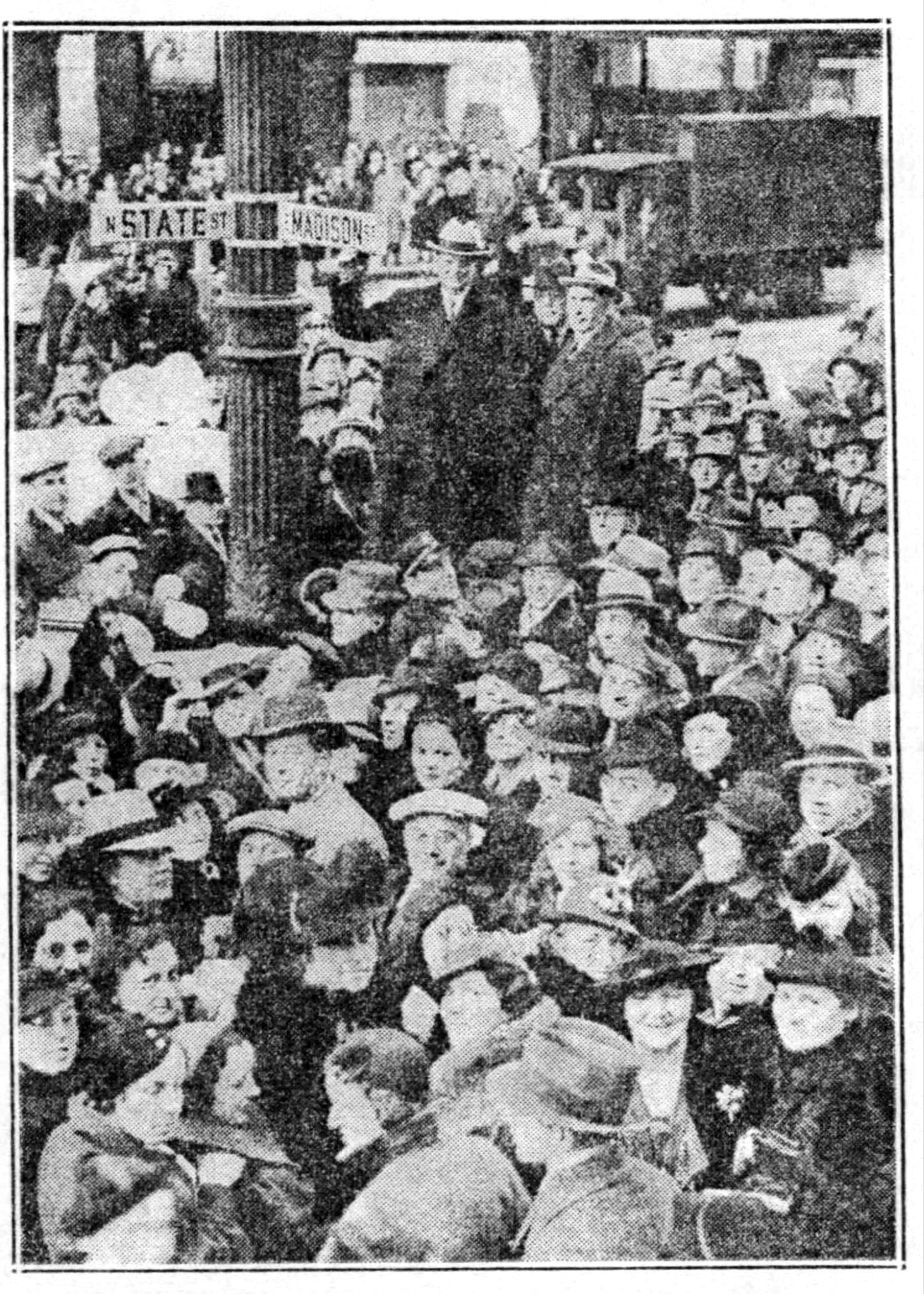 Crowd around Mayor Kelly at State and Madison yesterday as he put up first new marker. With him are Commissioner of Public Works Hewitt (center) and D. K. Kennicott of PWA.