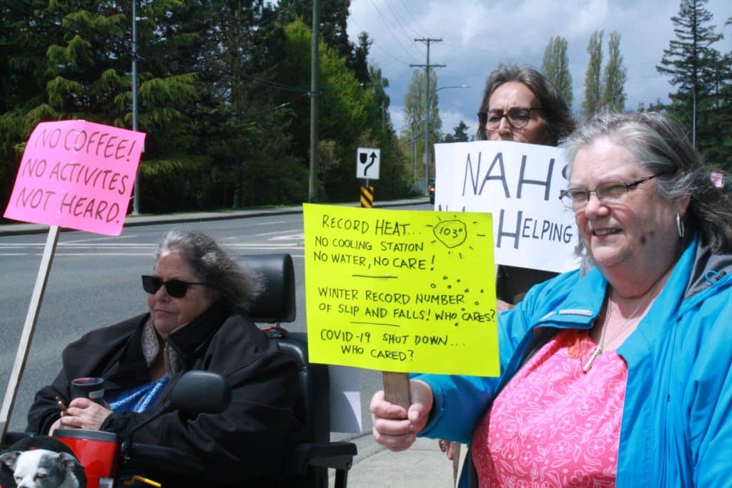Older adults holding out protest signs.