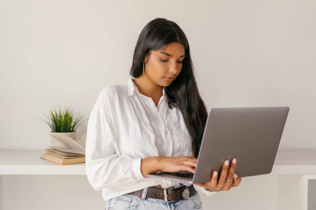 A woman in a white dress shirt using a laptop. Email series.