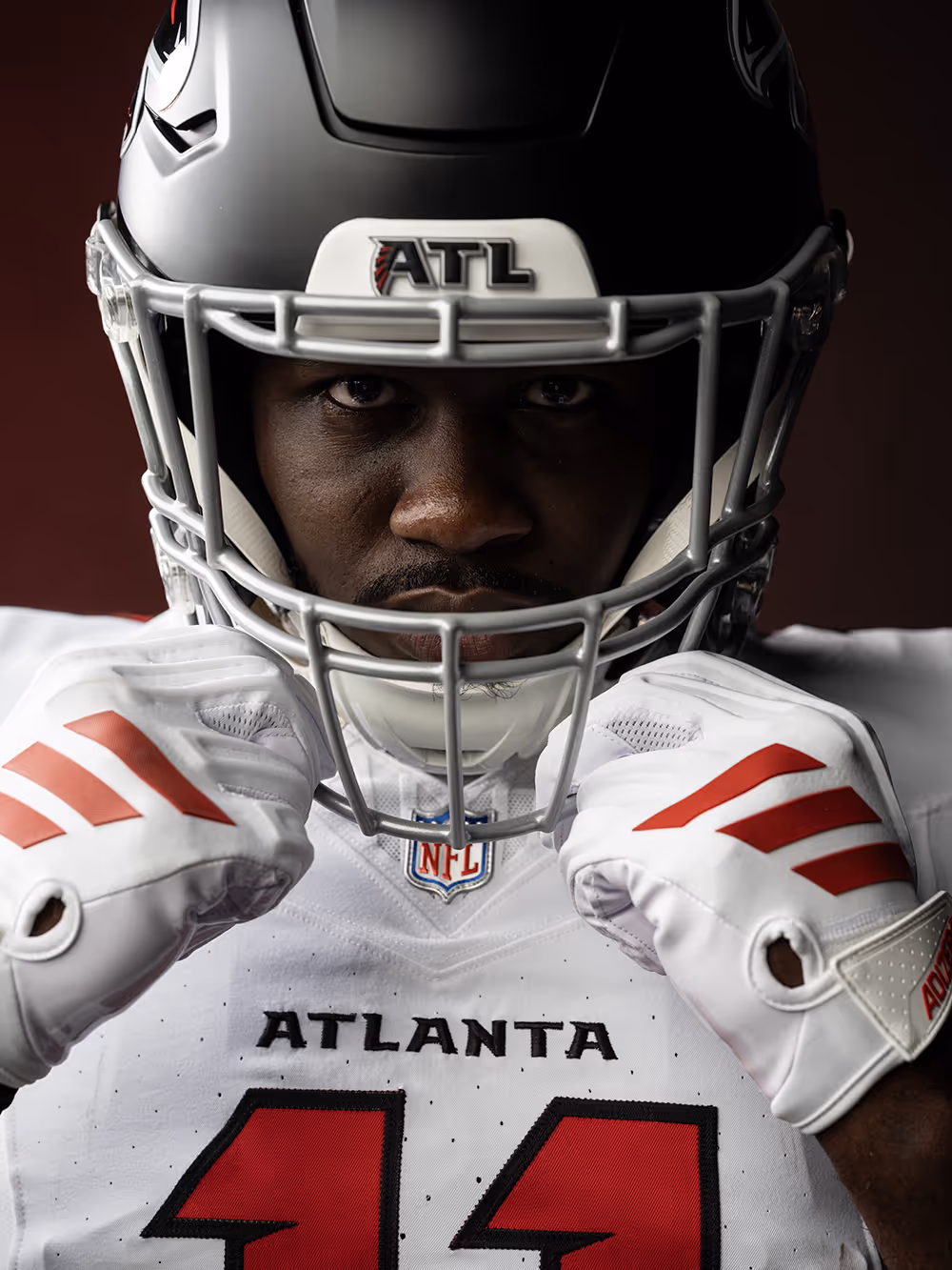 Close-up of an Atlanta football player wearing a black helmet and white jersey with number 11, adjusting his gloves.