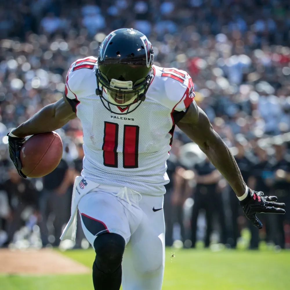 Atlanta Falcons football player wearing number 11 in white uniform running with ball on the field.