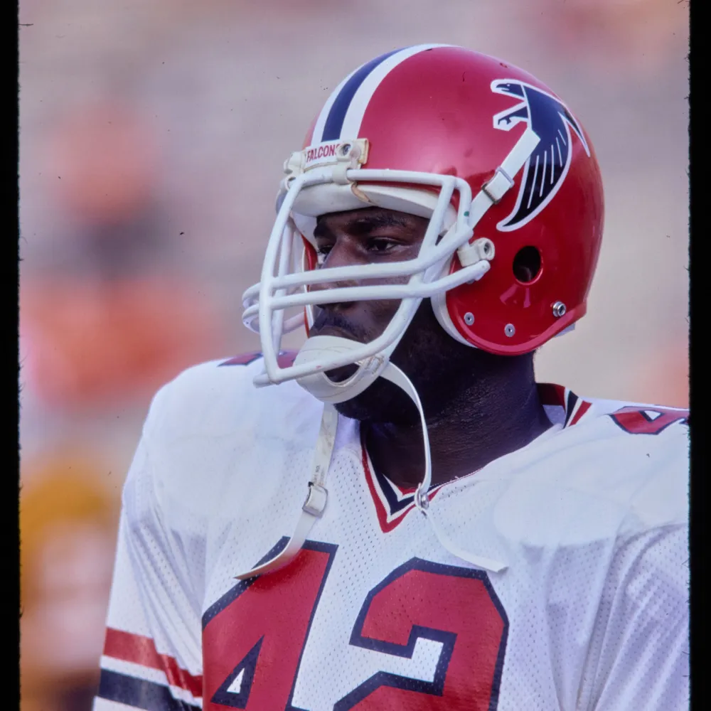 Atlanta Falcons football player wearing a red helmet with a black falcon logo and a white jersey with number 42.