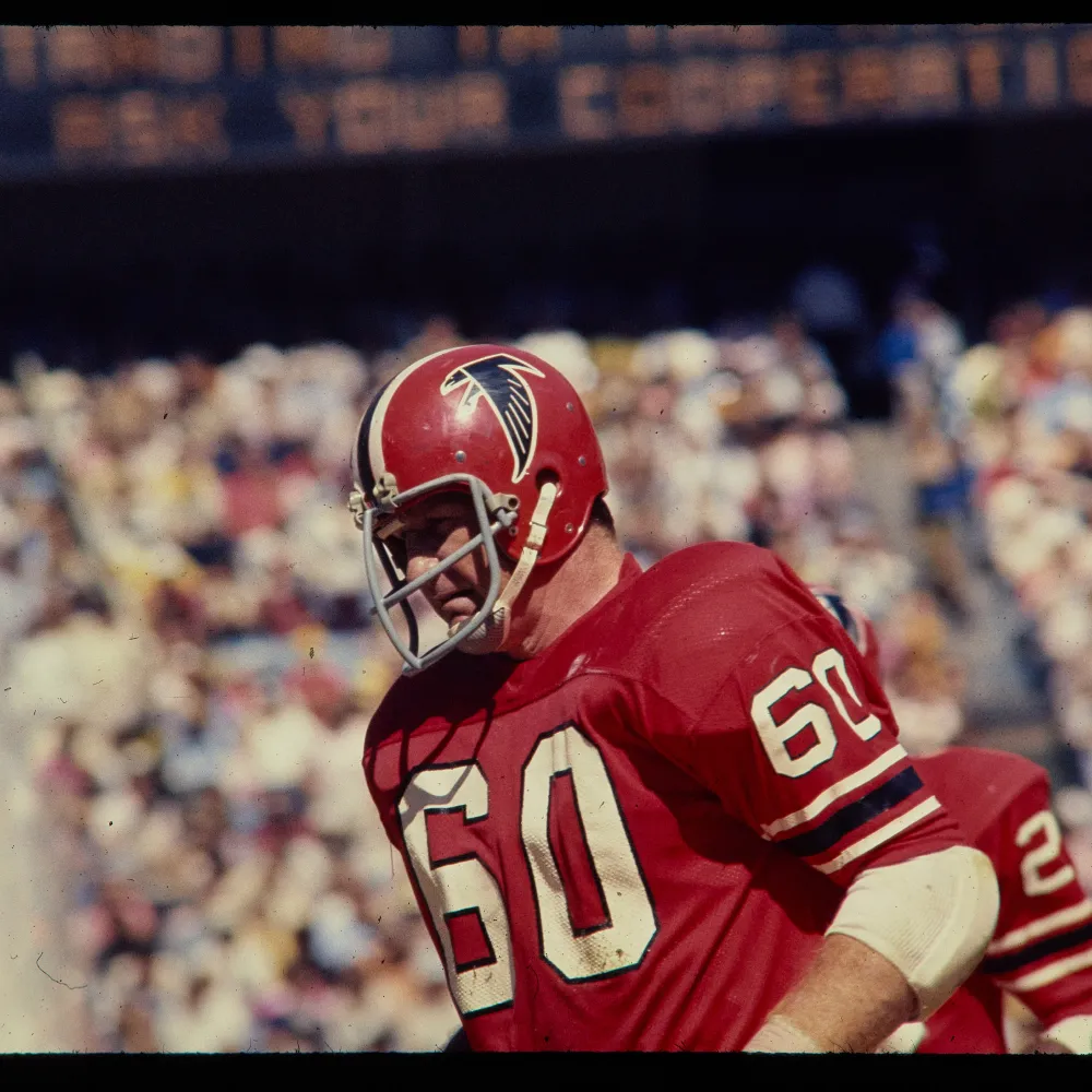 Football player wearing a red Atlanta Falcons uniform with number 60 and a helmet featuring the Falcons logo.