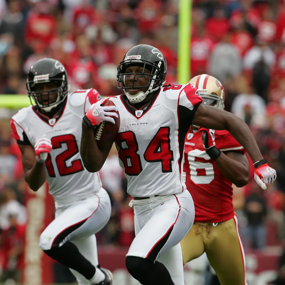 Atlanta Falcons football player number 84 running with a football during a game, pursued by teammates and a San Francisco 49ers player.