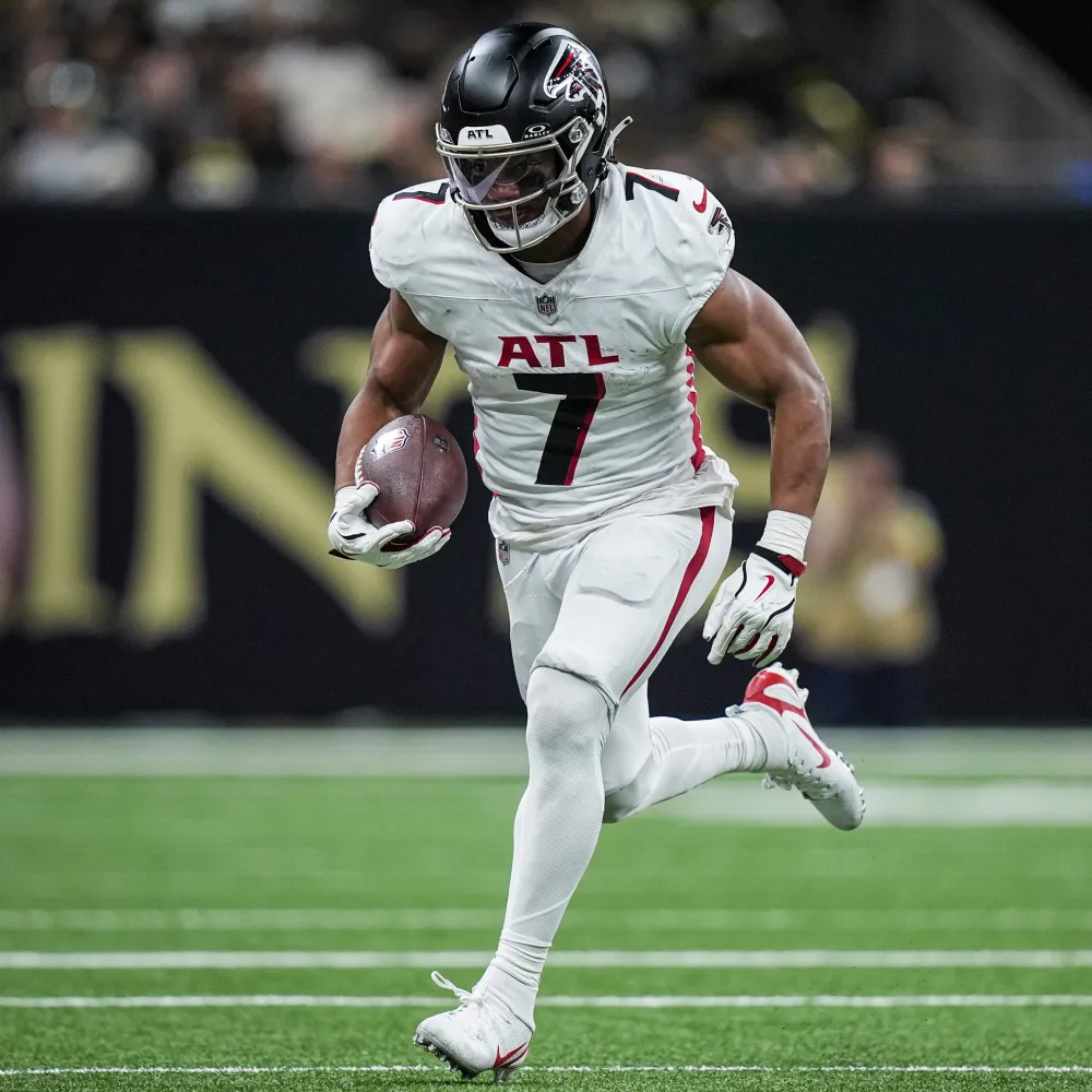 Atlanta Falcons football player in white uniform running with the ball on a football field.