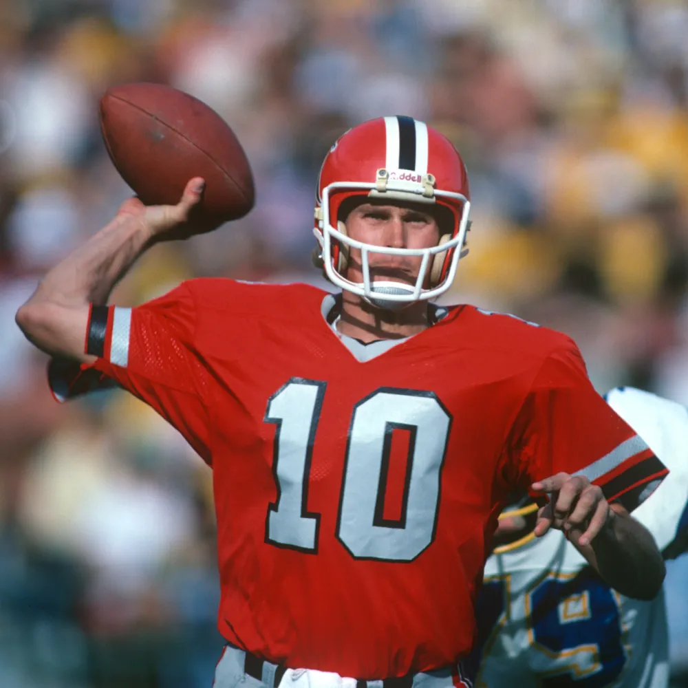 Football player wearing a red jersey with number 10 and a red helmet poised to throw a football.