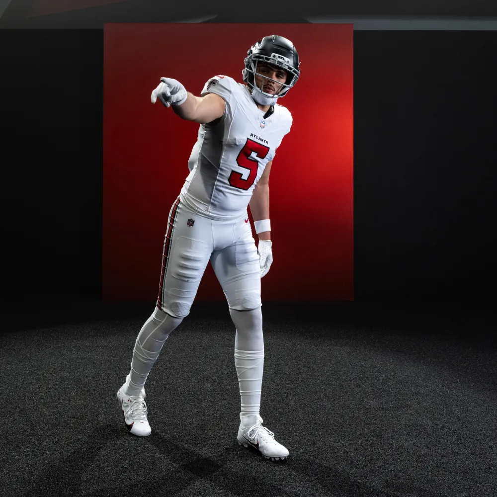 Atlanta Falcons football player in white uniform with red number 5 and black helmet pointing forward.