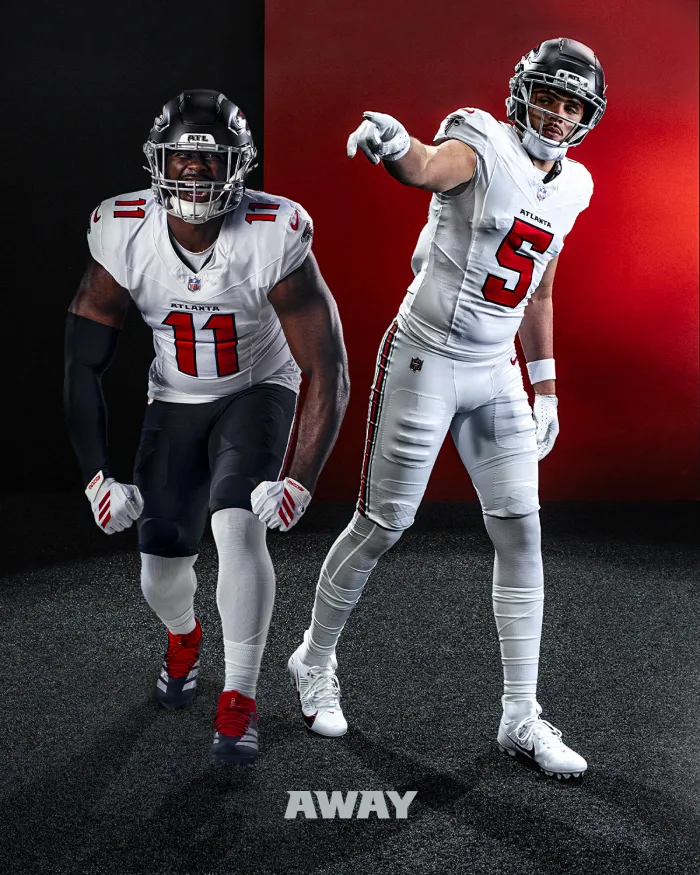 Two Atlanta Falcons football players wearing white away jerseys, black helmets, and one pointing forward, against a black and red background.