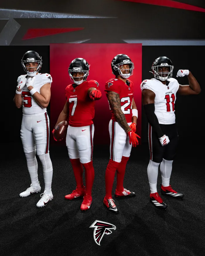 Four Atlanta Falcons football players standing in team uniforms showcasing 2026 jersey designs with black helmets on a black and red background.