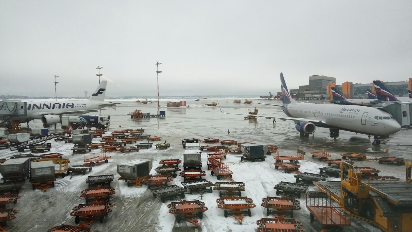Aircraft on the apron with cargo trailers lined up beside them.