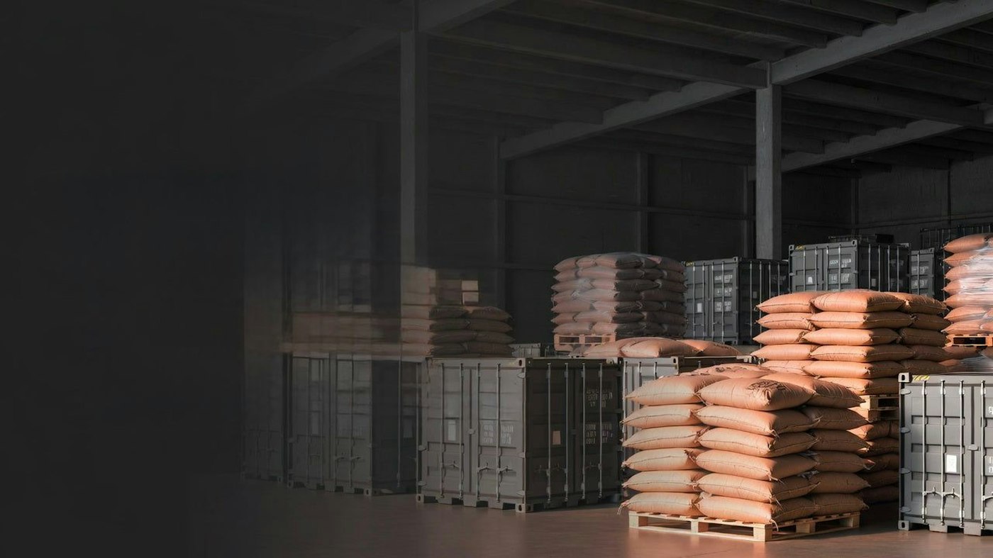 Stacked sacks and containers inside a freight warehouse.