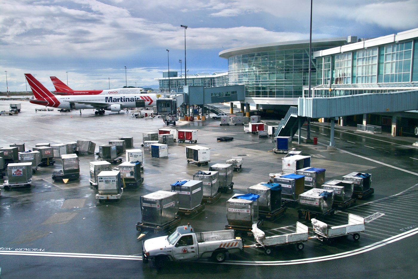 Airport tarmac with baggage and cargo carts parked beside an airplane.