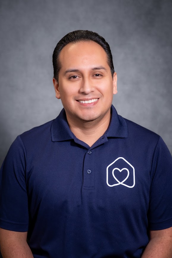 Marco Dominguez smiling in a navy polo shirt headshot