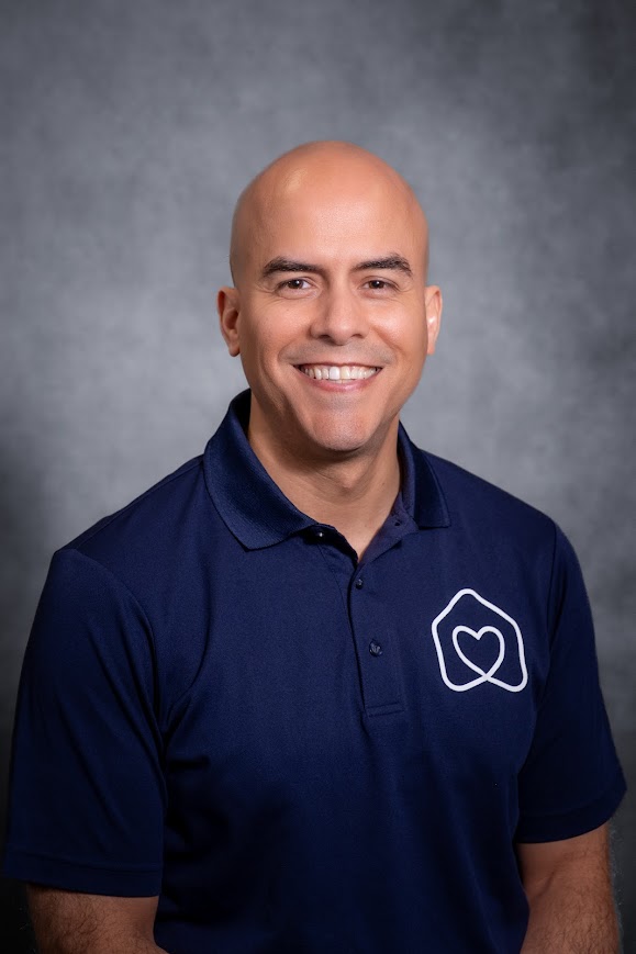 Jesse Sanchez smiling in a navy Hearts team polo shirt