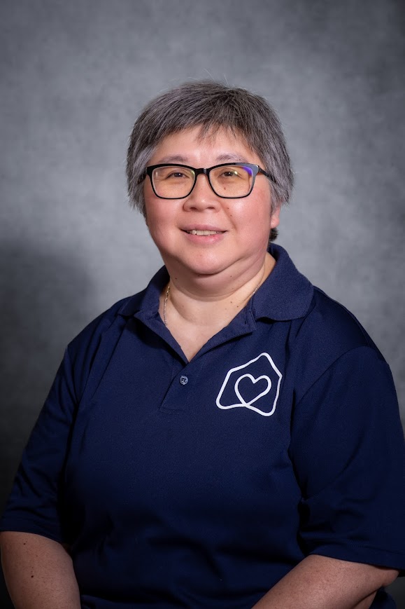 Phyllis Tam smiling in a navy school staff polo shirt