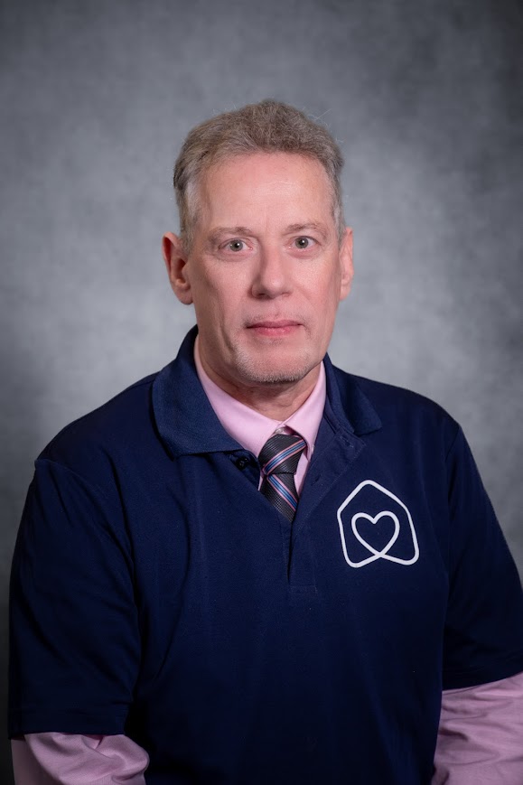 Dr. William Fahey in navy polo shirt and striped tie