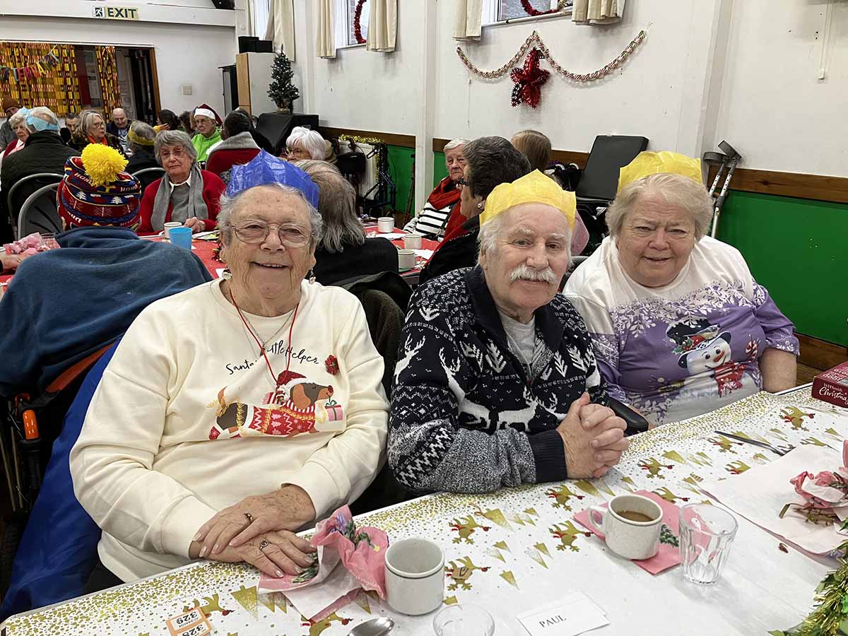 An image showing three people enjoying a Christmas lunch at a Food & Friendship event