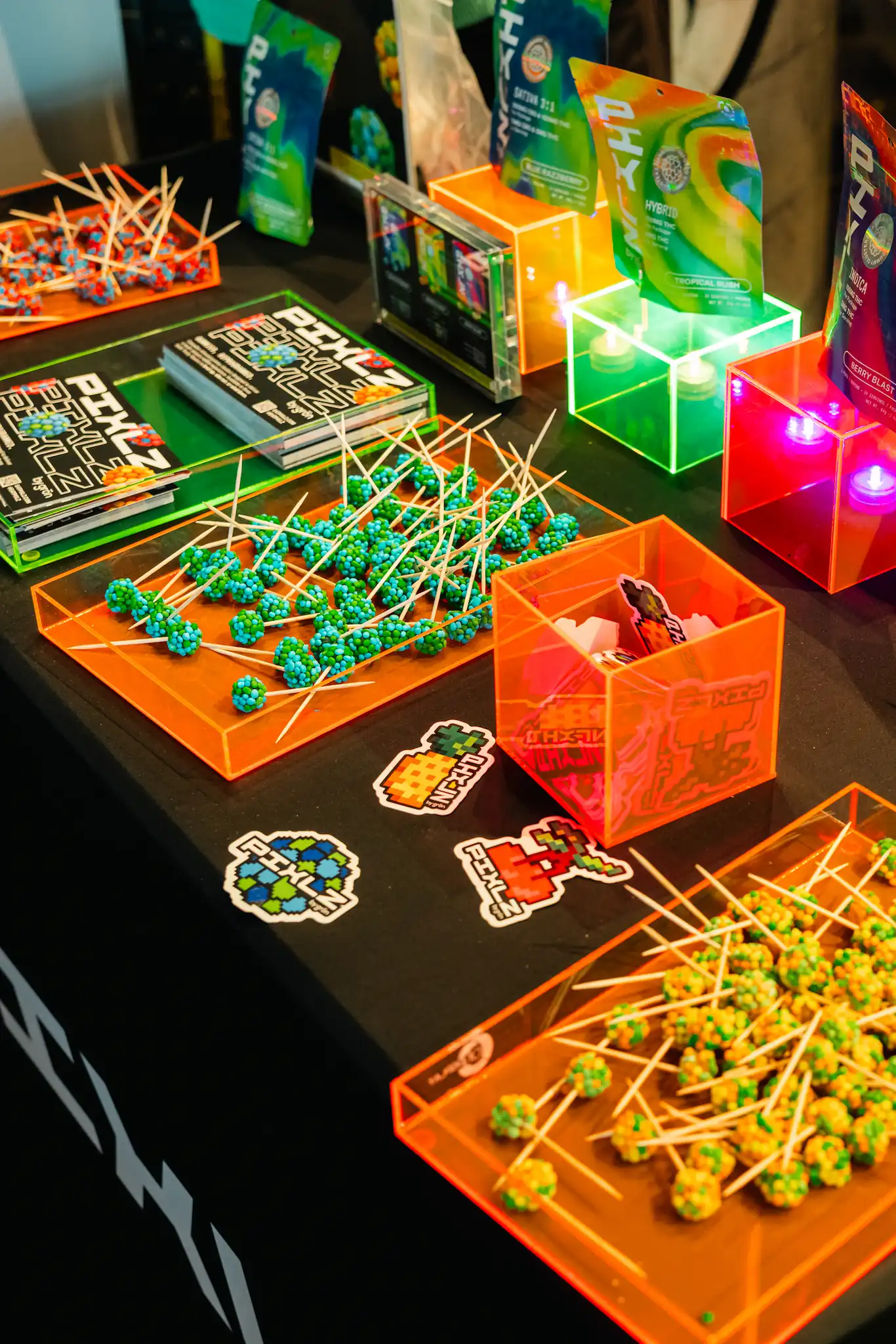 Table display with colorful candy lollipops, promotional stickers, and vibrant product packaging.