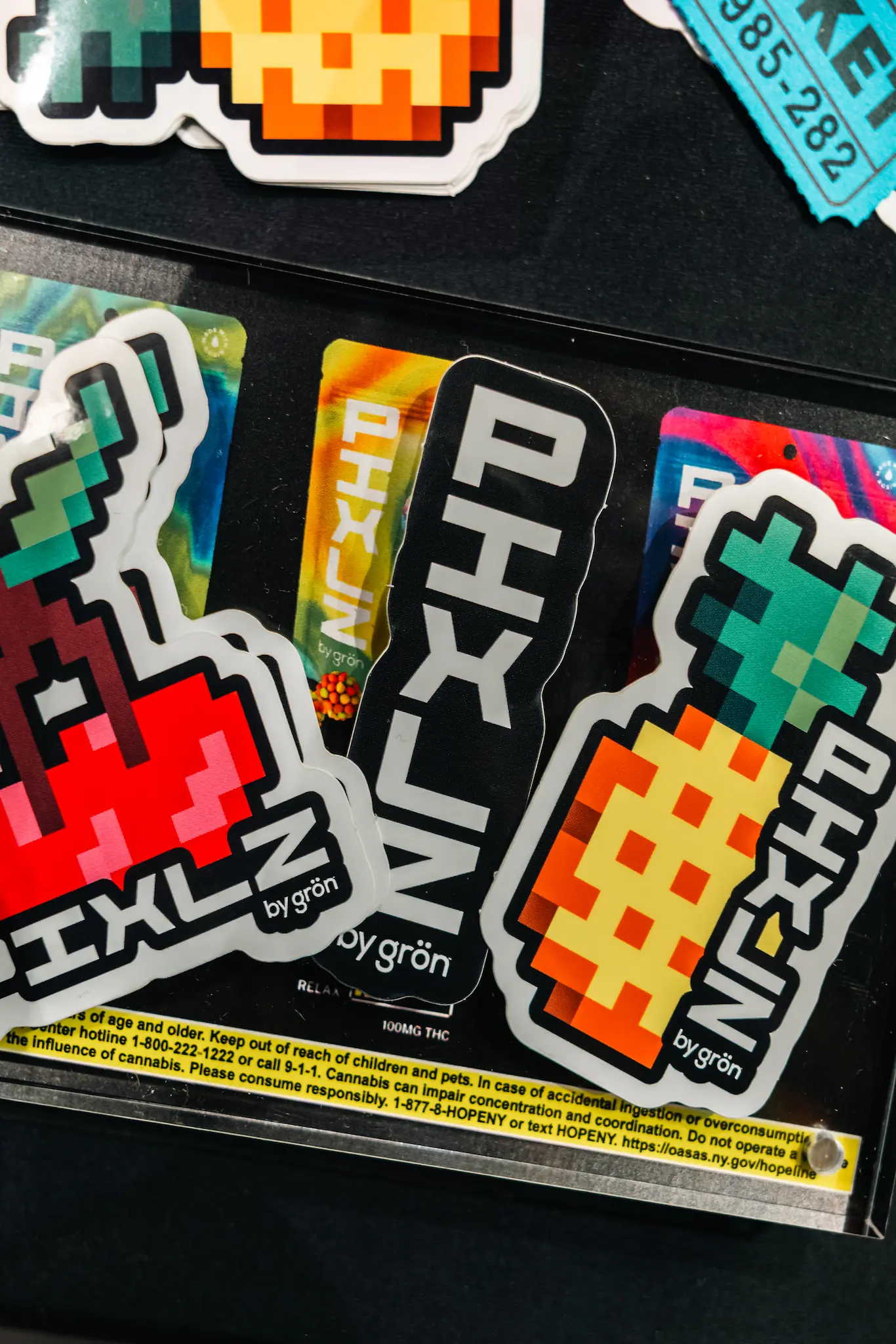 Colorful pixel art stickers of vegetables labeled PIXLZ by grön on a black surface with warning text.