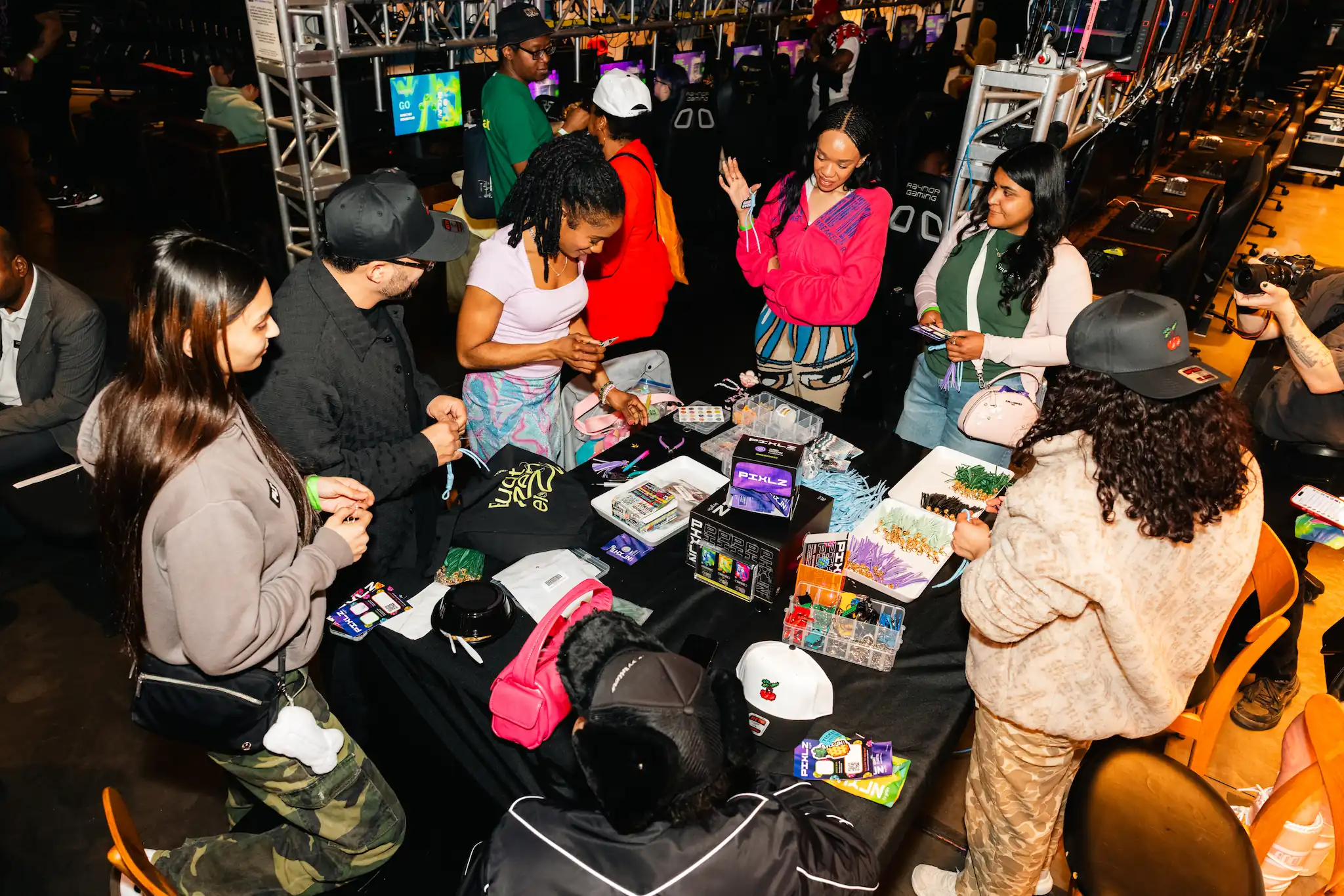 Group of people around a table making crafts with colorful supplies at a gaming event.