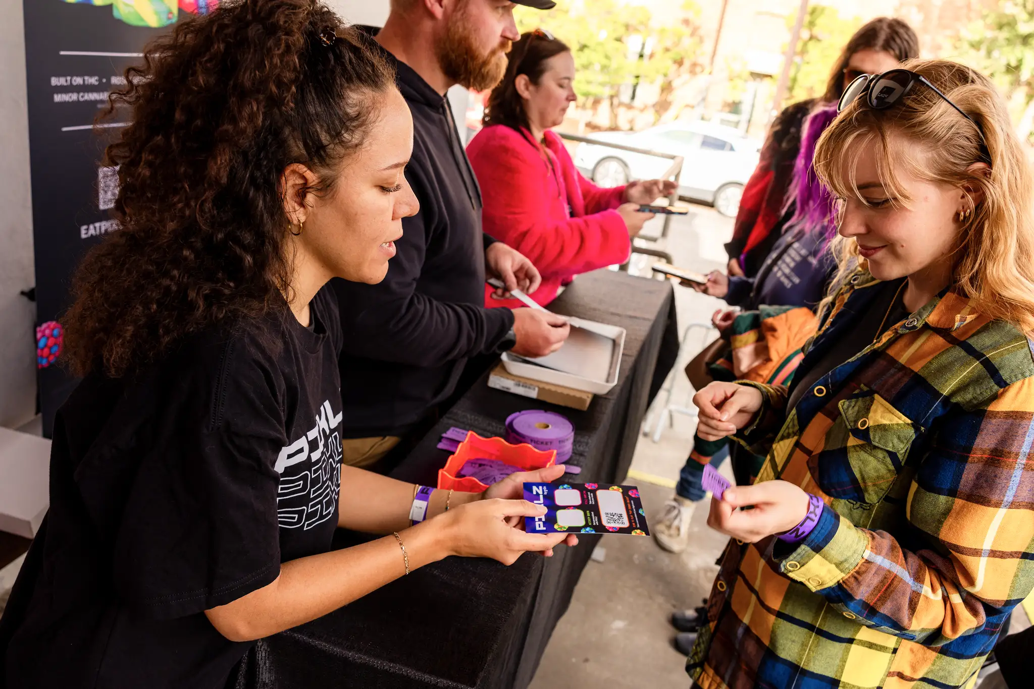 Man in green hoodie explains Pixlz gummy products to a woman at a promotional booth.