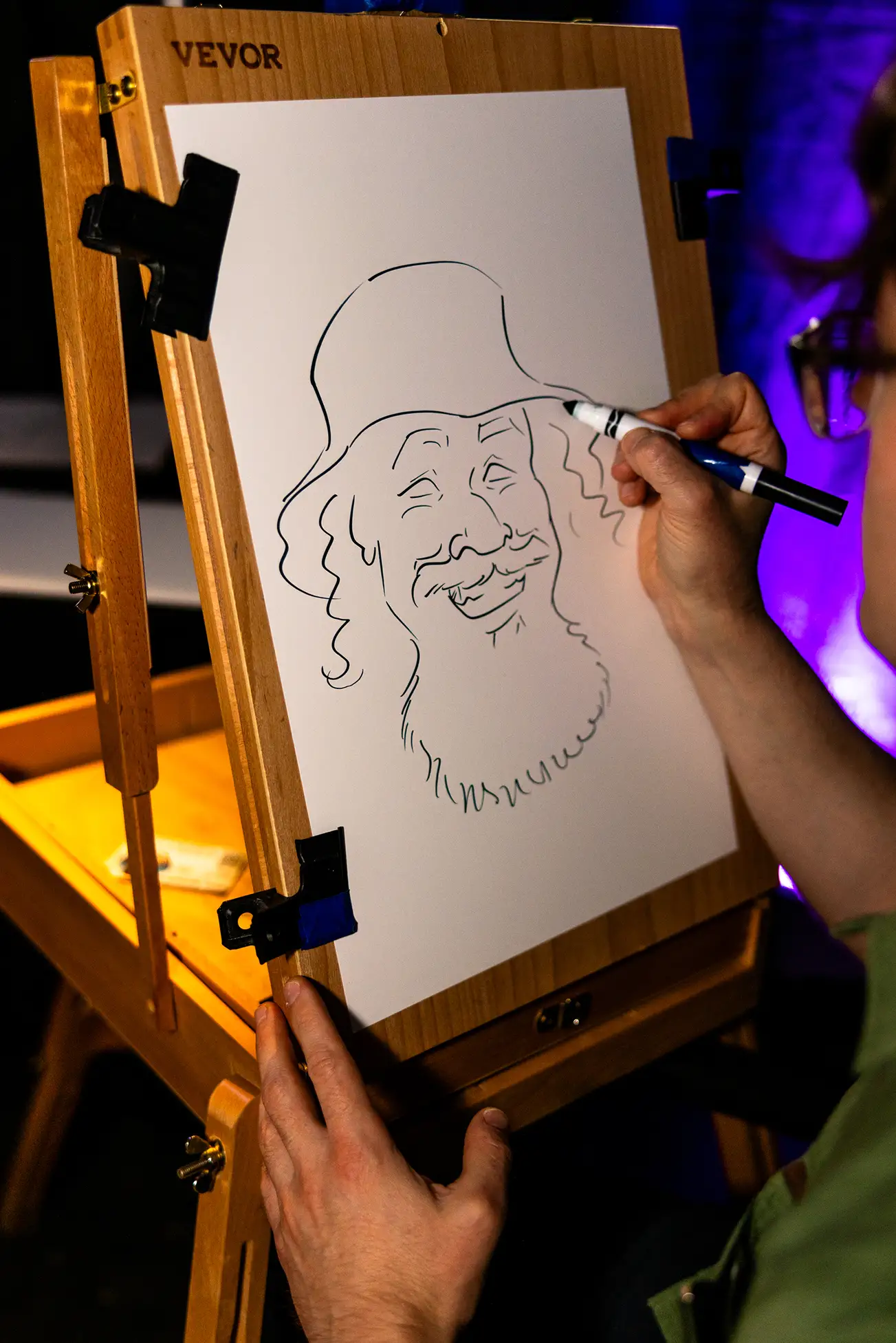 Person wearing a black cap and bandana holds colorful candy sticks over their closed eyes and smiles wide.