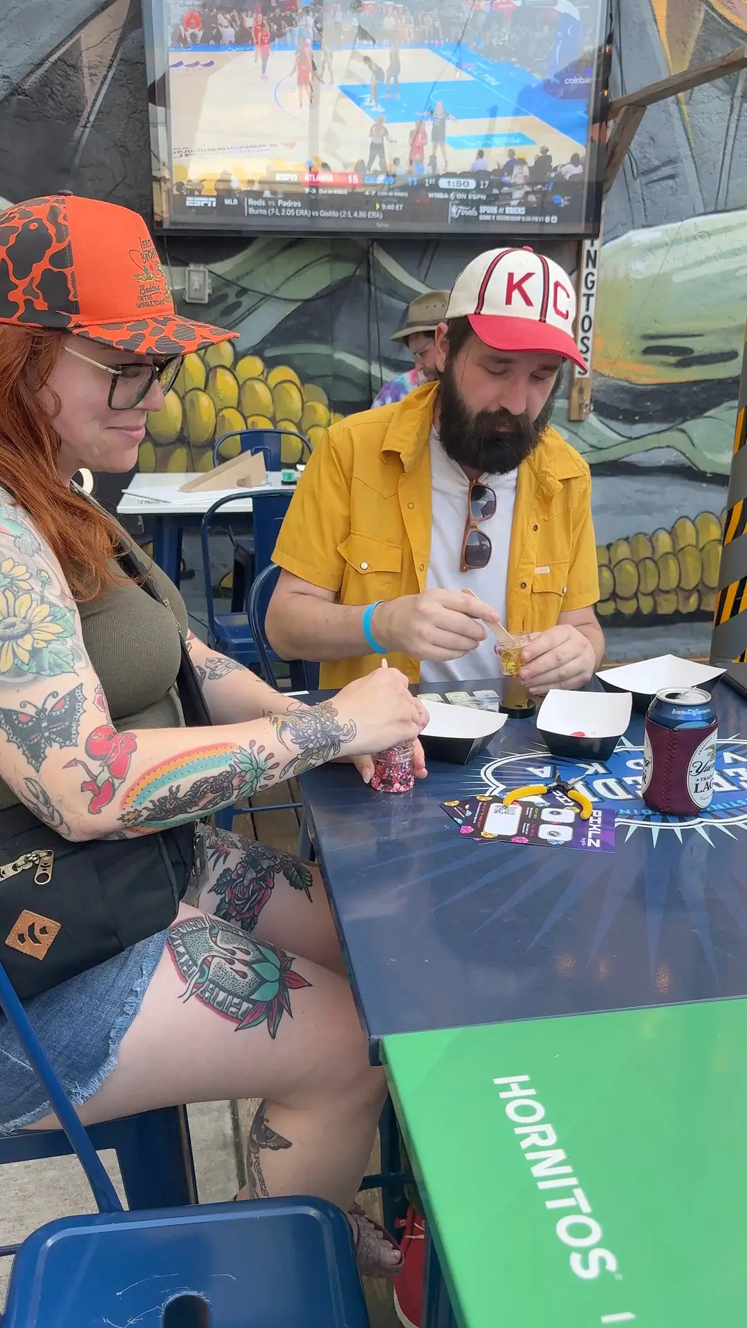 Three smiling people at a booth under a tent, one holding a tray with small green and blue PIXLZ on toothpicks.