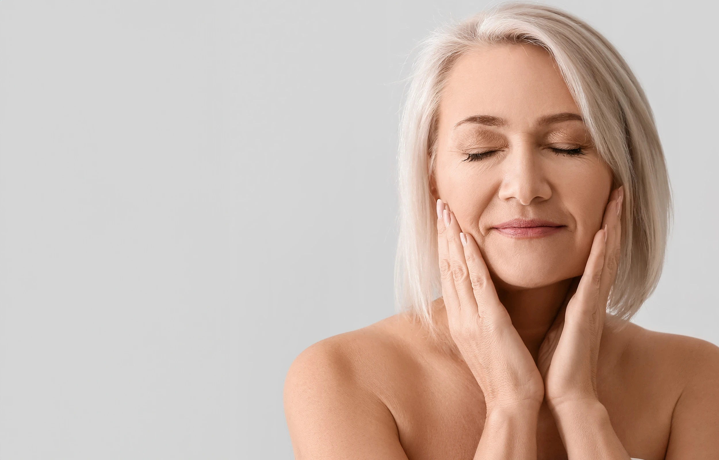 A woman smiling, touching her face