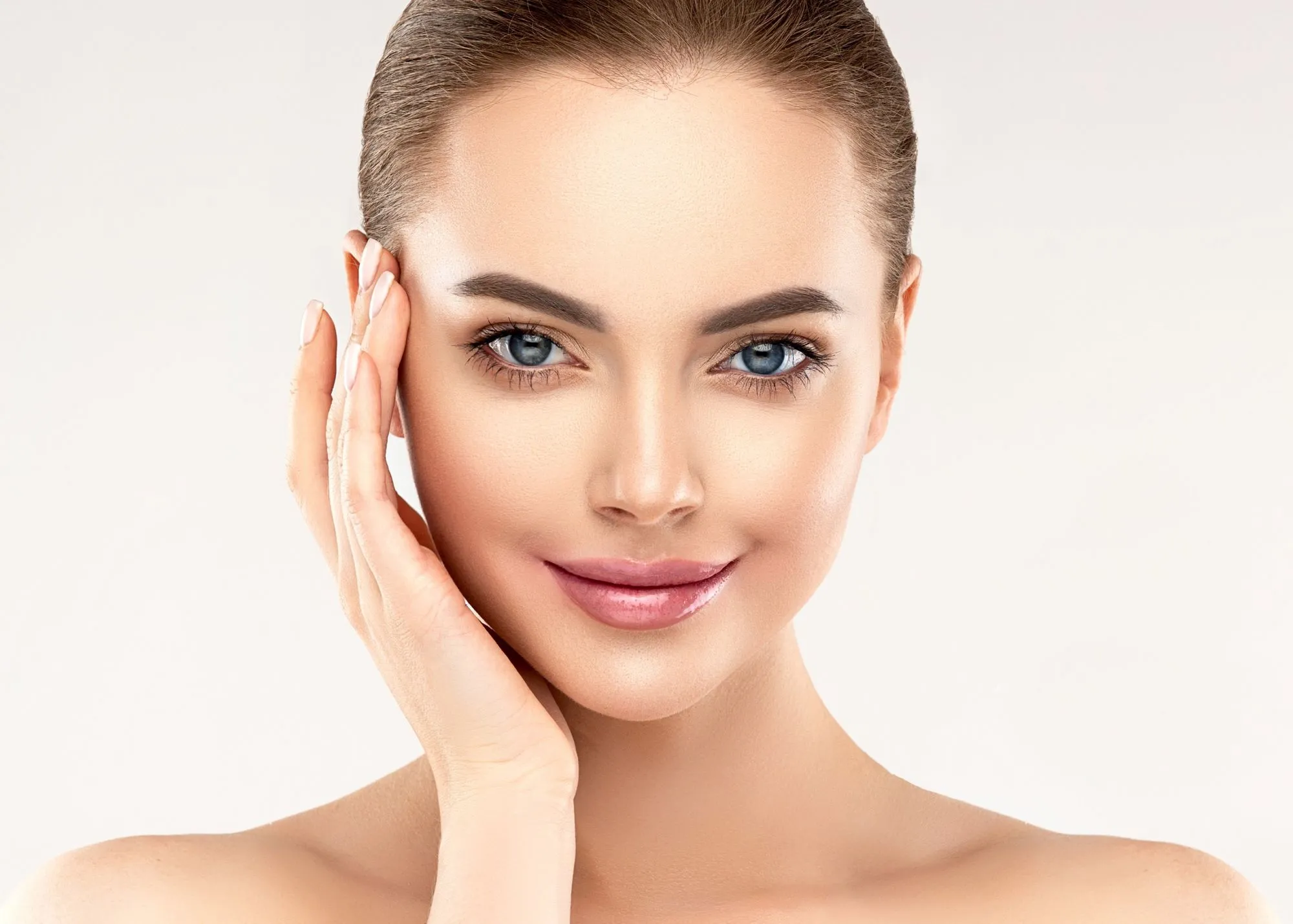 A woman smiling, touching her face