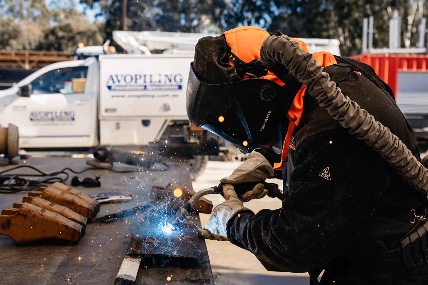 Interior view of a large industrial warehouse containing various heavy machinery, equipment, tools, and cables scattered on the concrete floor.