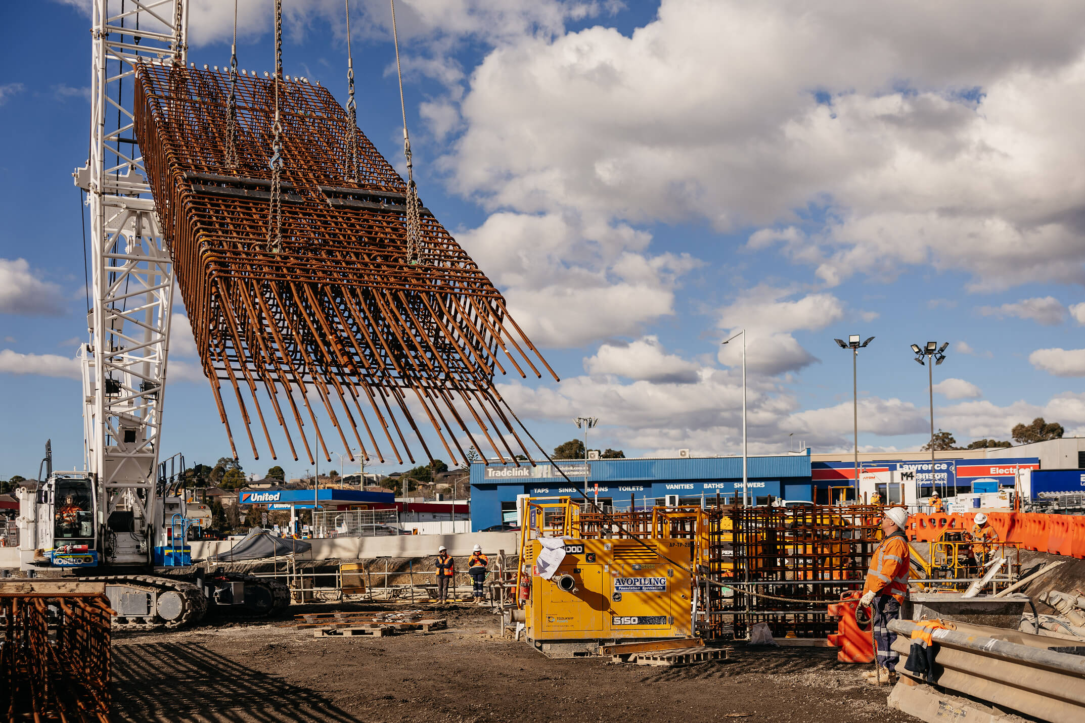 Grayscale photograph of a construction worker in a safety harness operating from an elevated lift platform.