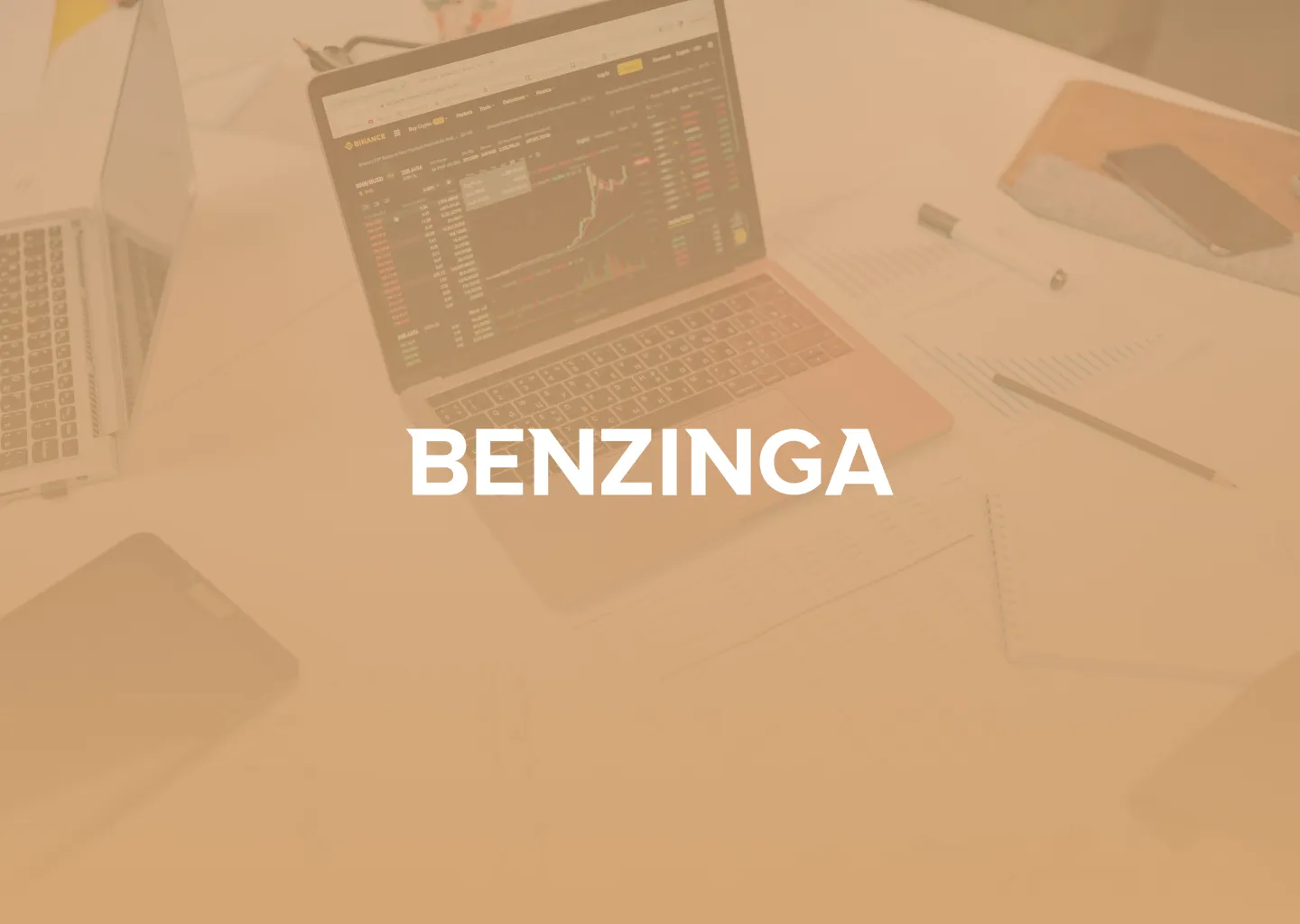 Benzinga logo over a desk with a laptop and calculator, tinted yellow