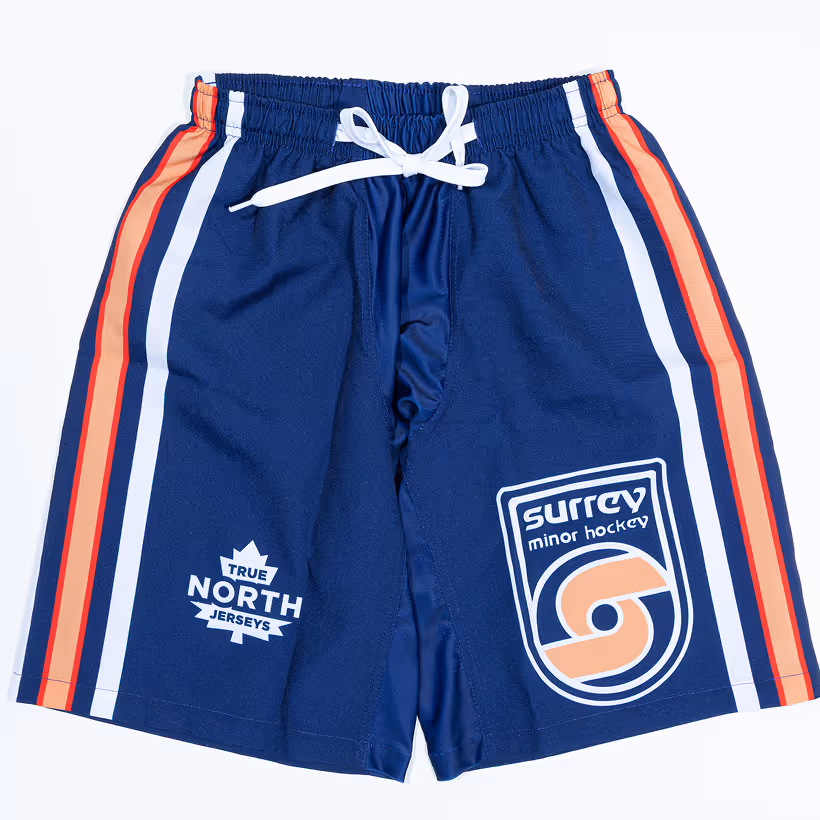 Navy blue sports shorts with white, red, and orange stripes on the sides, featuring logos for Surrey Minor Hockey and True North Jerseys.