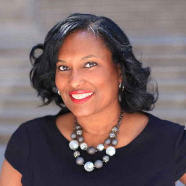 Headshot of Onida Coward Mayers smiling, wearing a black top and statement necklace.