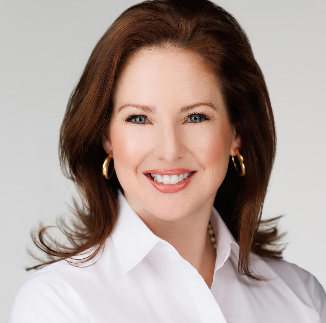 Headshot of Lindsey Williams Drath smiling, wearing a white blouse and gold earrings.