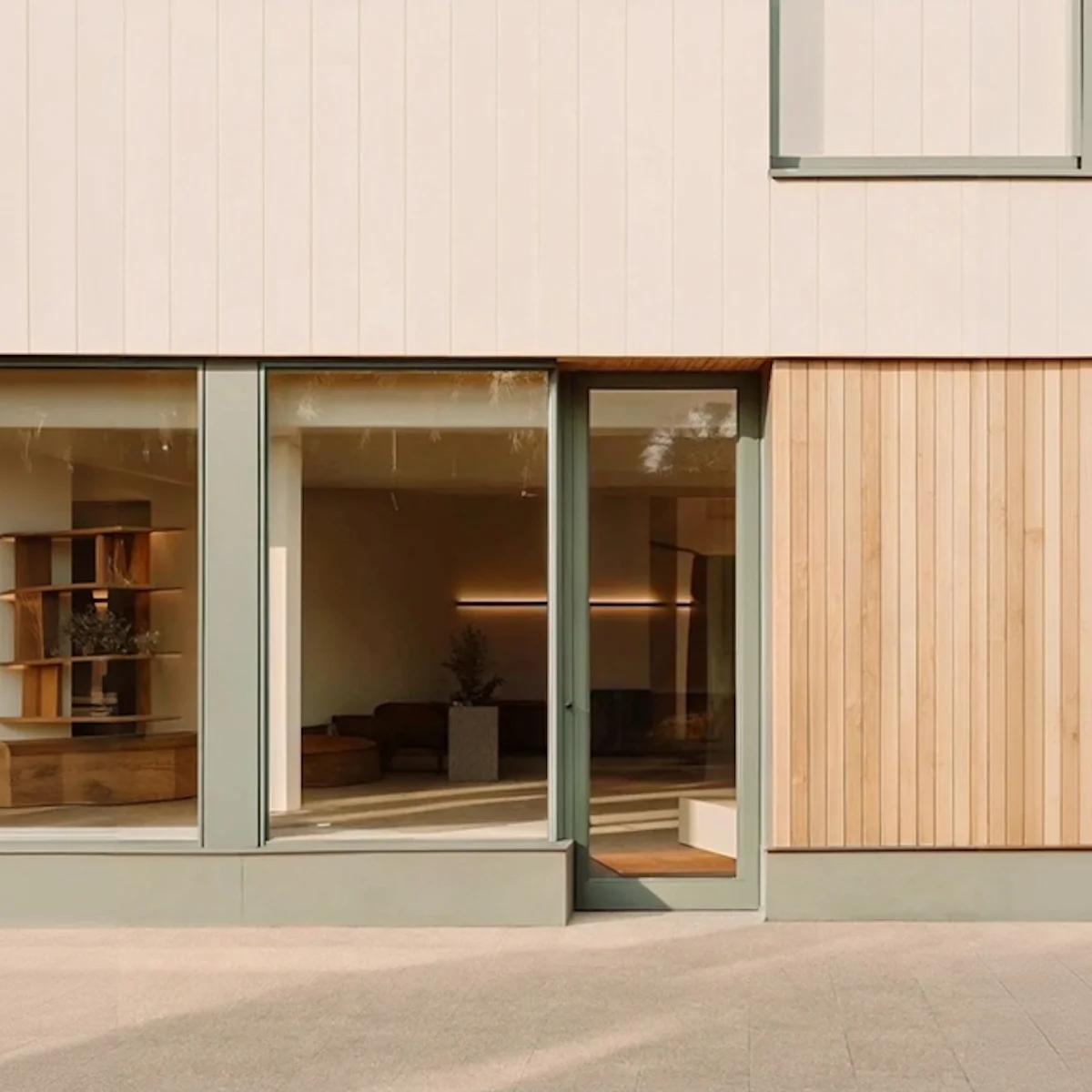 Modern building facade with large glass windows, a glass door, and wood paneling on the right side.