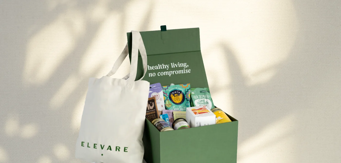 Green box filled with assorted healthy food products and a white tote bag with the word ELEVARE beside it on a light background.