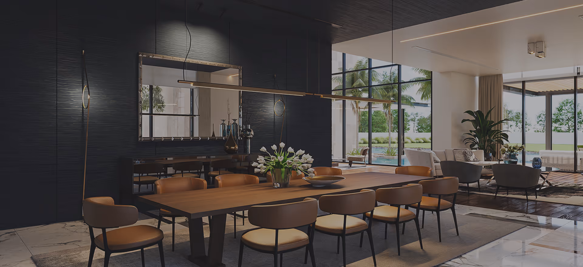Modern dining room with a long wooden table surrounded by brown chairs, a vase of white flowers as centerpiece, large mirror on dark wall, and a view of an outdoor pool through large windows.