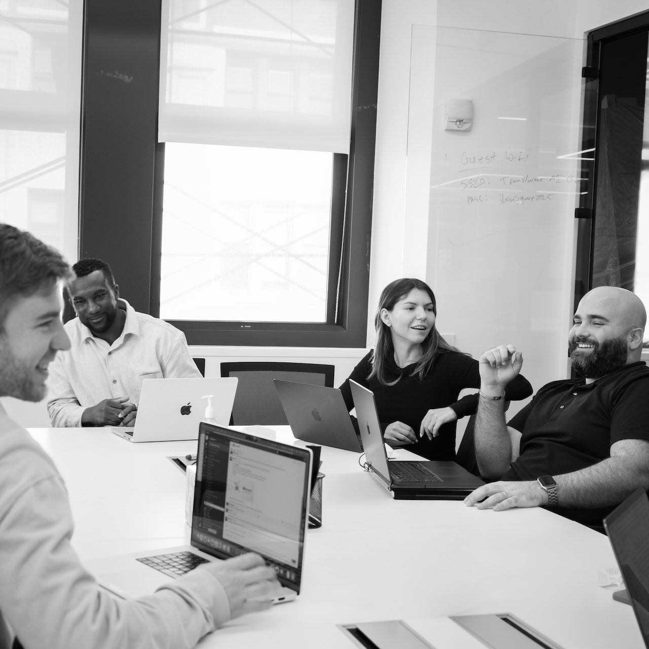 Translucent team members laughing during a meeting in the office conference room