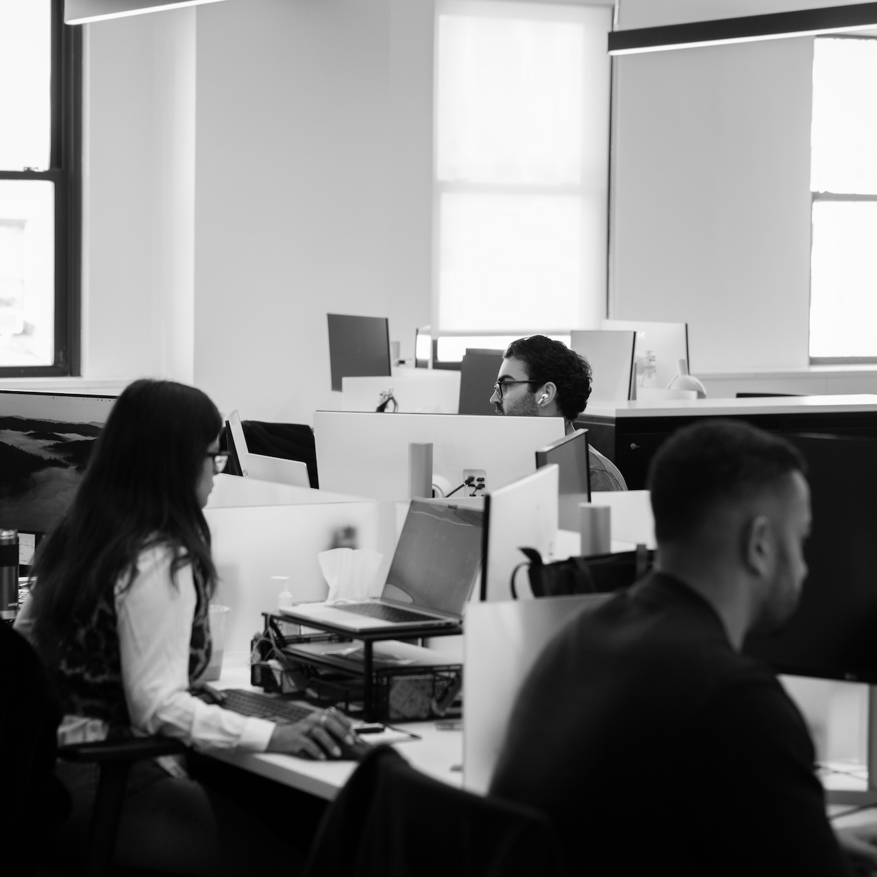 Translucent employees collaborating across desks in the open-plan office