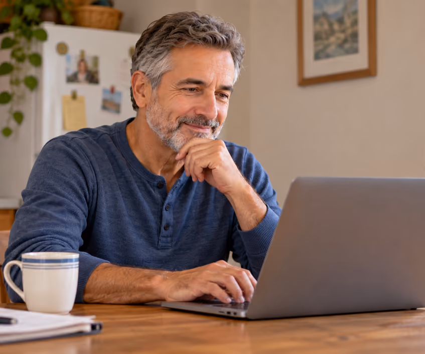 Man sitting at kitchen table with laptop submitting a request for AI-supported prostate MRI analysis.